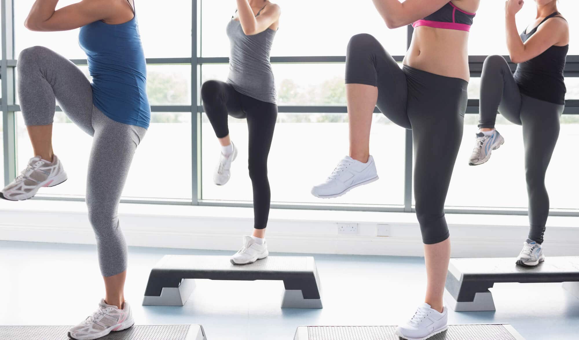 Women raising their legs while doing aerobics in gym