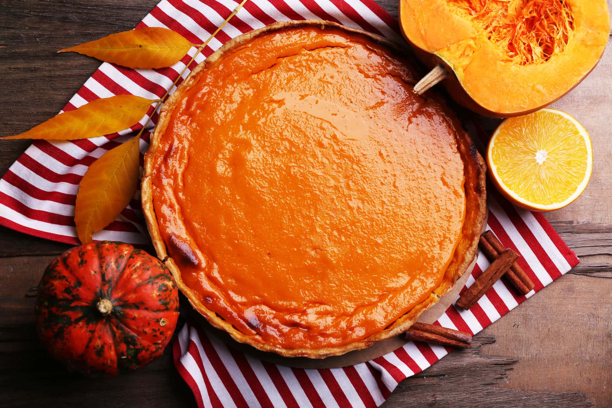 Homemade pumpkin pie on napkin, on wooden background.
